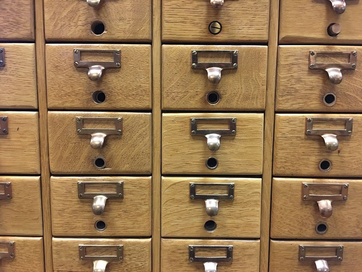 Rows of wooden card-catalogue drawers with handwritten labels
