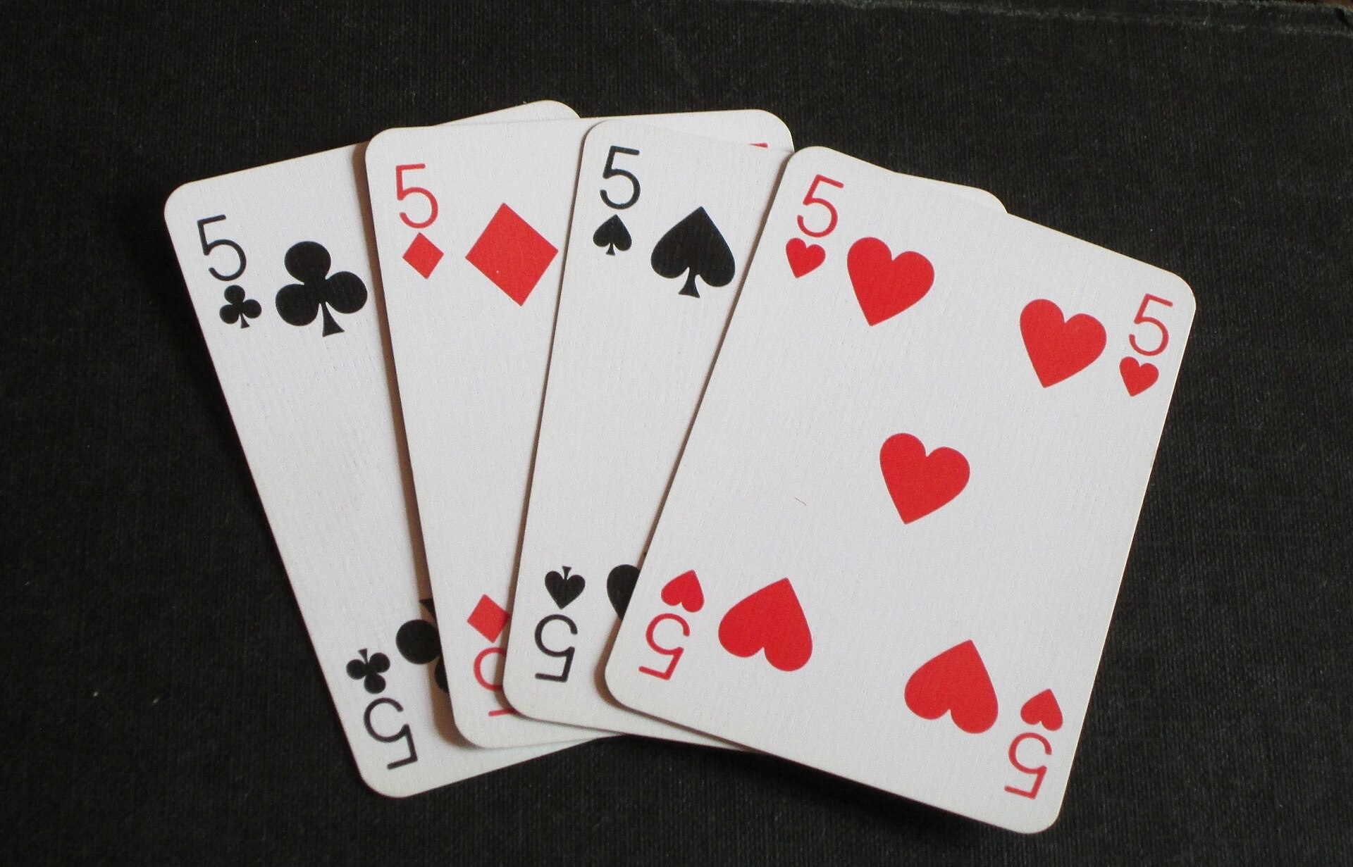 Four playing cards fanned out: the five of clubs, diamonds, spades and hearts