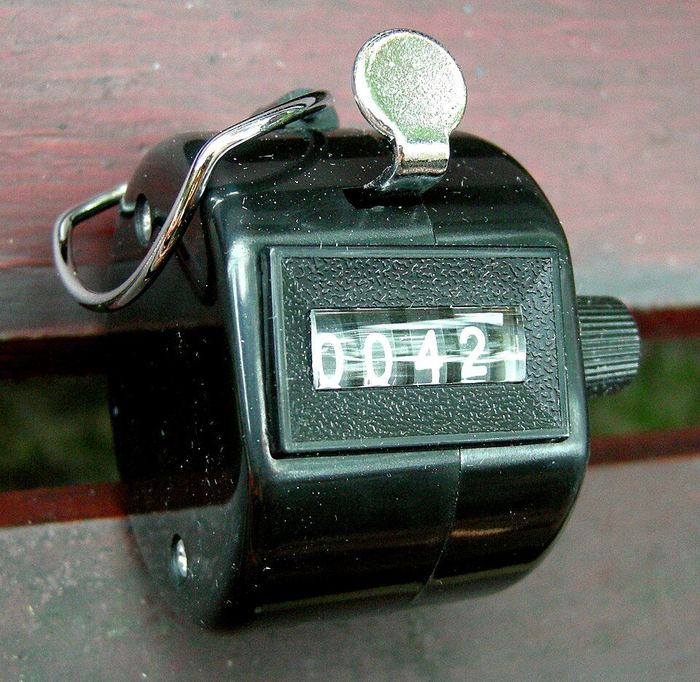A hand tally counter showing 0042 in its little window